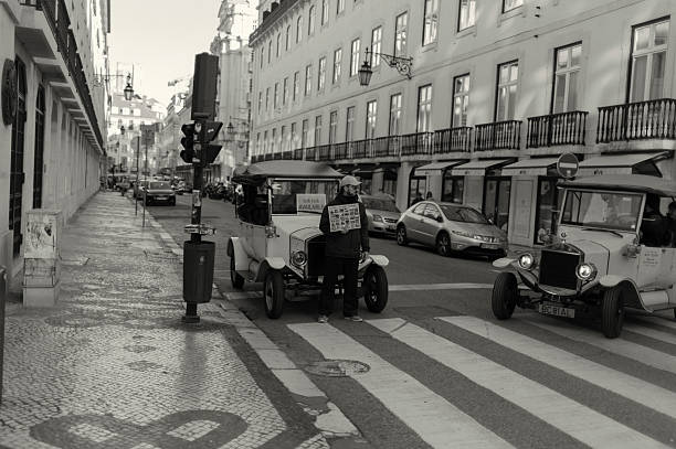 Lisbon, Portugal - January 18, 2025: A tuk-tuk driver waits for clients while holding a menu card by is tuk-tuk in a street in Lisbon downtown.