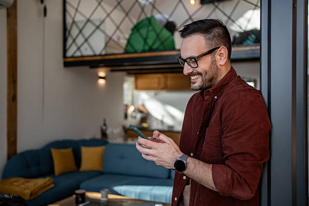 istock Smiling man using smartphone at home in modern apartment 2205545667
