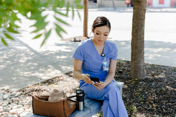 istock Nurse using smartphone outdoors, healthcare professional break 2205549551