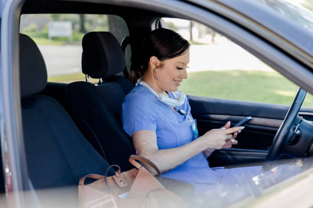 istock Nurse using smart phone in car, healthcare worker 2205549565