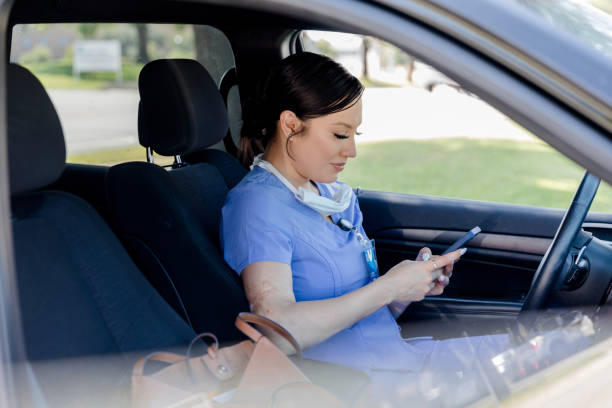 istock Nurse using smart phone in car, healthcare worker 2205549570
