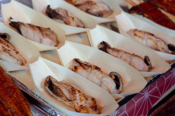 Delicately grilled exotic white fish with a slightly charred surface is arranged in wooden trays at a seafood market in Tokyo prepared for sampling