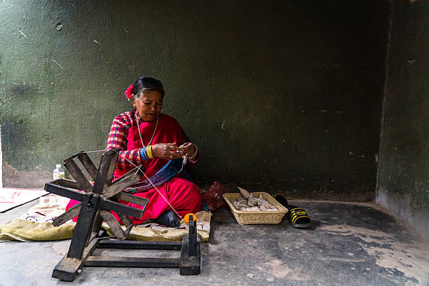 An elderly  poor Indian woman speaking during an interview in India. The woman is wearing a red and orange scarf and a purple sweater. Her expression is serious as she speaks.
