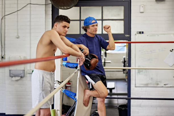 istock Trainer and teen standing in blue corner watching sparring 2205555751