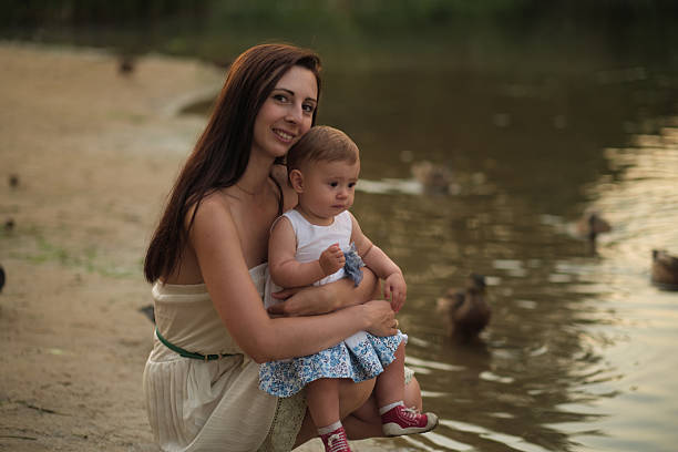 istock Calm waters and a mother's gentle hold create a peaceful scene, ducks in the backdrop. It illustrates the growing movement towards eco-conscious parenting. 2205557177