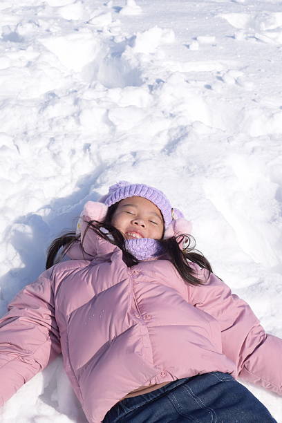Girl wearing pink coat and sleeping in snow.