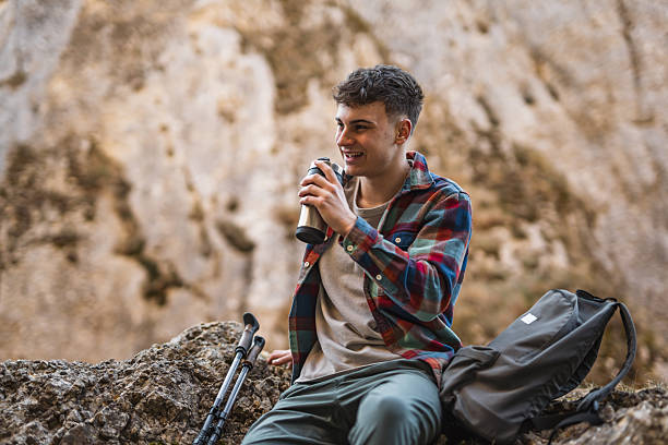 istock relax young man hiker sit on rock and drink coffee in forest 2205558641