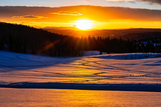 istock Orange Golden Hour Light Reflecting on Snow with Snowmobile Tracks 2205558930