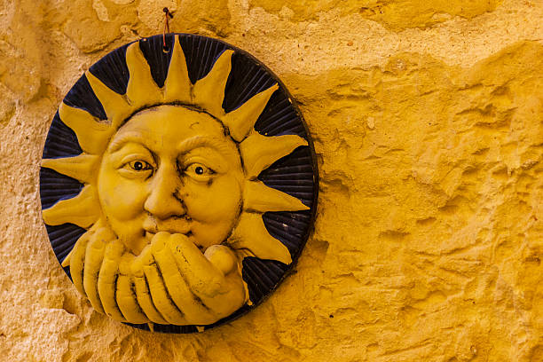 A vibrant ceramic wall hanging featuring a sun face against a rustic yellow textured background adds warmth and artistic charm to any space.