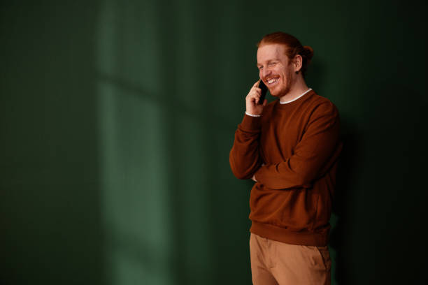 istock Young man with red hair and beard smiling while talking on the phone 2205559330