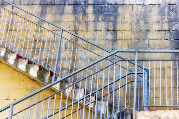 A rustic outdoor metal staircase against a weathered brick wall, showcasing urban decay and aesthetic simplicity. Ideal for illustrating architectural, construction, or urban exploration themes in artistic projects.