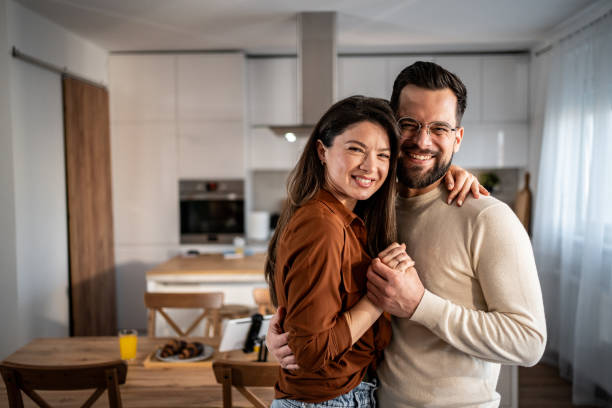 istock Happy couple embracing and smiling in their modern kitchen 2205559525