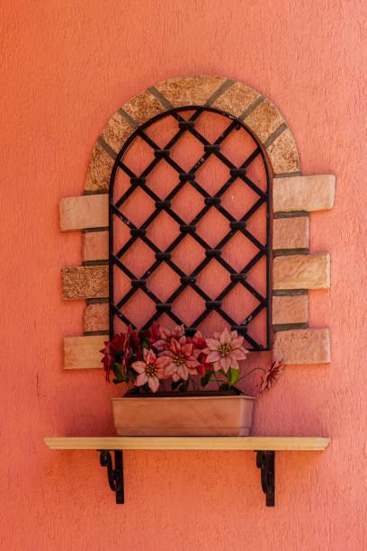 istock Decorative Wall Design with Potted Flowers and Arched Metal Frame on Pink Background 2205559532