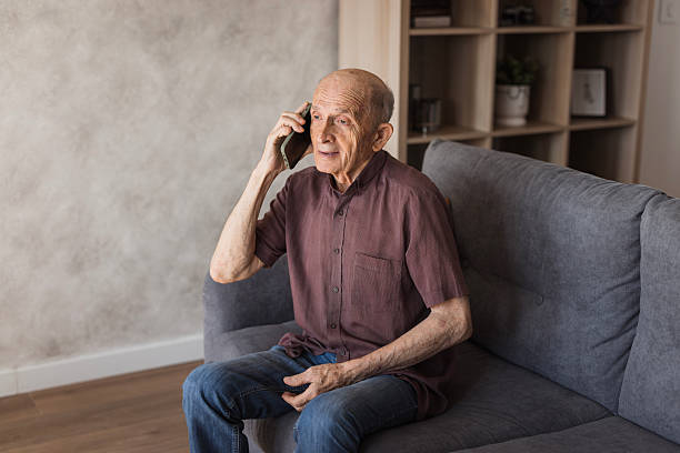 istock Smiling mature man using smartphone at home 2205560939