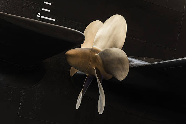 Detailed view of a metallic submarine propeller attached to a black hull, showcasing the engineering design. Suitable for maritime and industrial themes, highlighting mechanical components