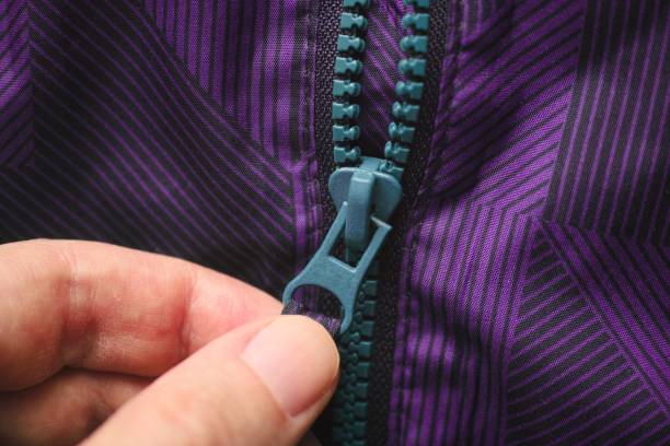 A person unzipping a purple jacket