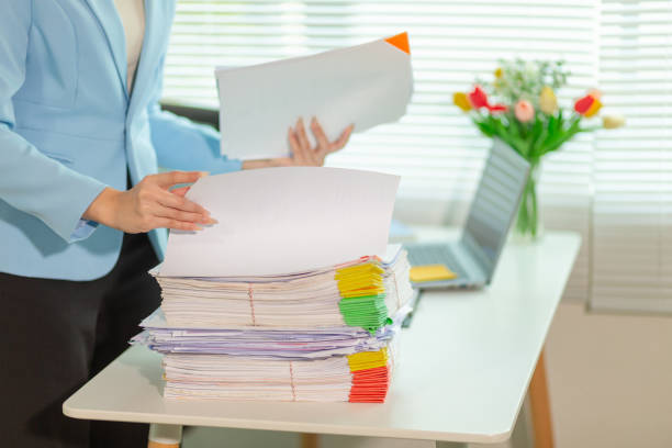 istock Businessman searching for important contract documents from pile of documents on table confirm agreement she signed with an investor. Businessman checking accuracy of documents she signed in contract 2205571694