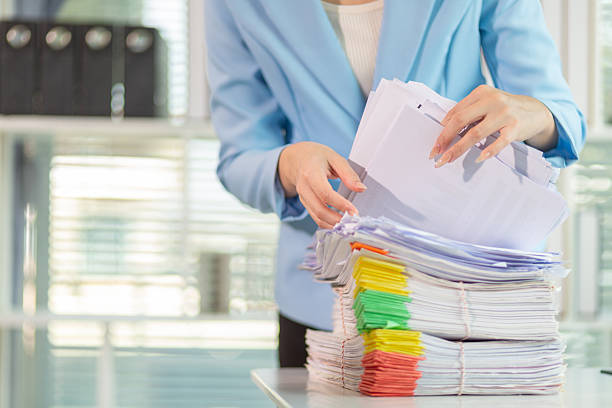istock Businessman searching for important contract documents from pile of documents on table confirm agreement she signed with an investor. Businessman checking accuracy of documents she signed in contract 2205571735