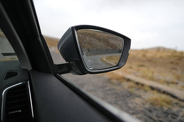 Rearview mirror in water droplets. Car wash in the garage. Wet machine. Transport details.