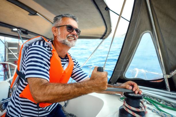 Mature man on the sailing boat using a winch
