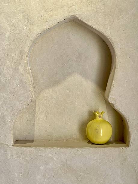 istock Yellow pomegranate placed in an arched alcove on a textured wall 2205575338