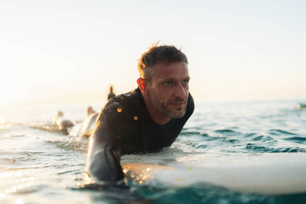 Photo of a male surfer in the ocean, wearing a wetsuit and warming up for surfing