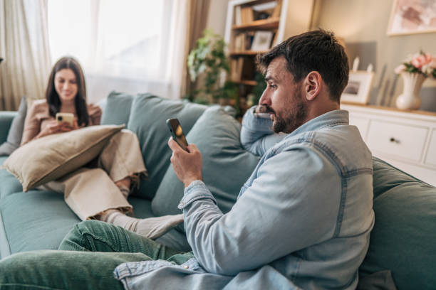 istock Couple ignoring each other while using smartphones on sofa at home 2205576728
