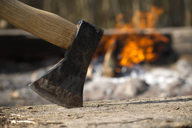 istock A sharp axe stands ready to chop logs next to a warm and inviting campfire in the woods. 2205577073