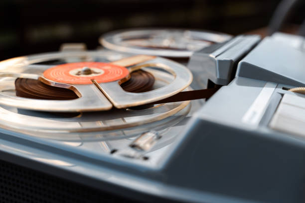 Close-up of a vintage reel-to-reel tape recorder with reels and tape visible, showcasing retro technology and design.