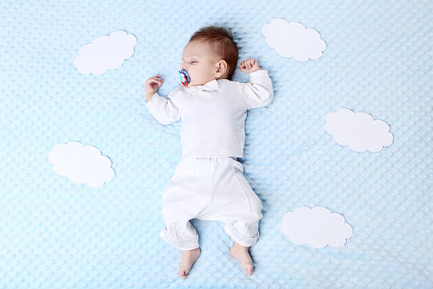 istock Cute baby with white paper clouds sleeping in bed 2205577810