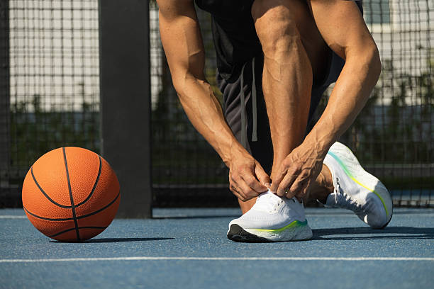 istock Basketball player tying running shoes shoelace before training. 2205578367