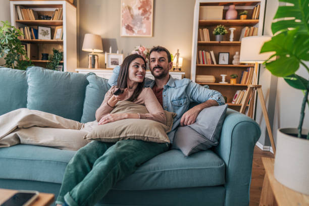 istock Young couple relaxing on sofa and watching television 2205580140