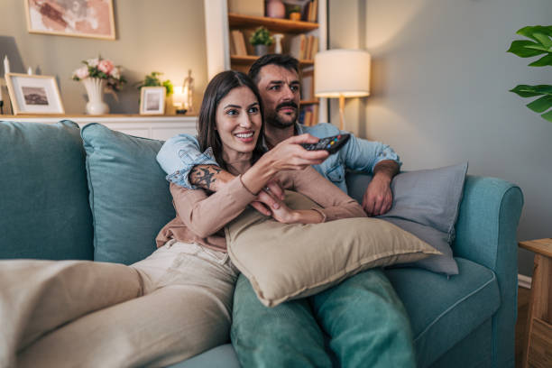 istock Young couple relaxing on sofa watching television at home 2205580251