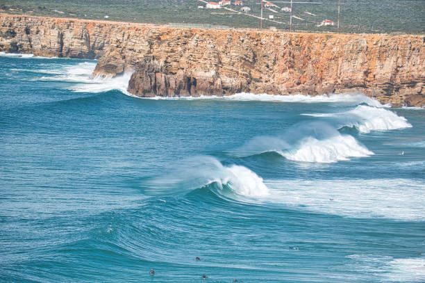 istock Surfers in the water with waves and cliffs 2205583673