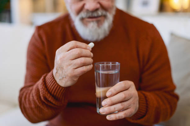 istock Senior man medicating himself with medicine at home 2205583980