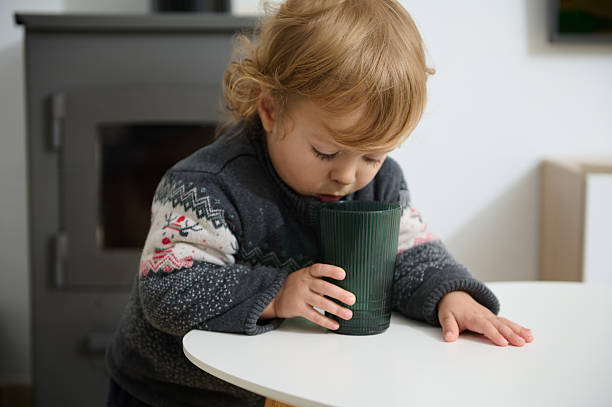 istock Young Child in Sweater Drinking From a Cup in a Cozy Room 2205584187