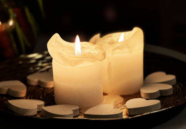 Burning candle standing on a windowsill late in the evening night.