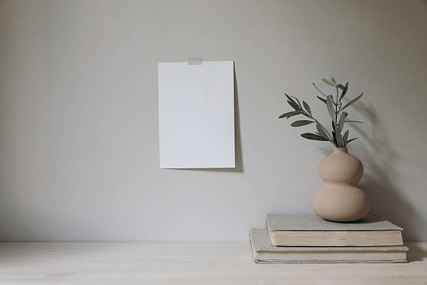 istock Blank greeting card mockup taped on beige wall.Organic shaped vase with green olive tree branches. White wooden office desk, table with old books. Empty copy space. Elegant minimal still life. 2205584637