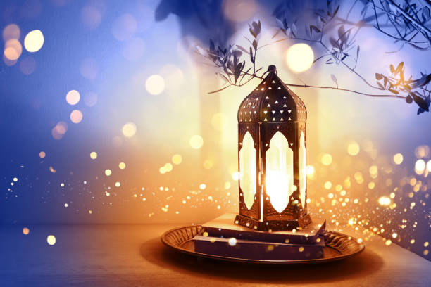 istock Ornamental dark Moroccan, Arabic lantern on table burning at night. Glittering magical bokeh lights. Greeting card for Muslim community holy month Ramadan Kareem, Eid Mubarak. Festive background. 2205584641