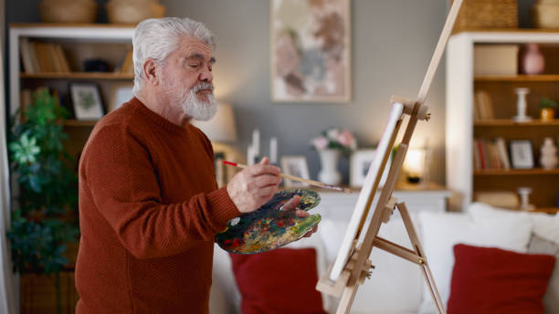 istock Senior man draws on canvas in his home 2205586257