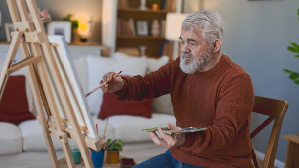 istock Senior man draws on canvas in his home 2205586260