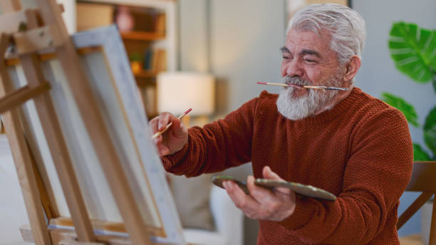 istock Senior man draws on canvas in his home 2205586273