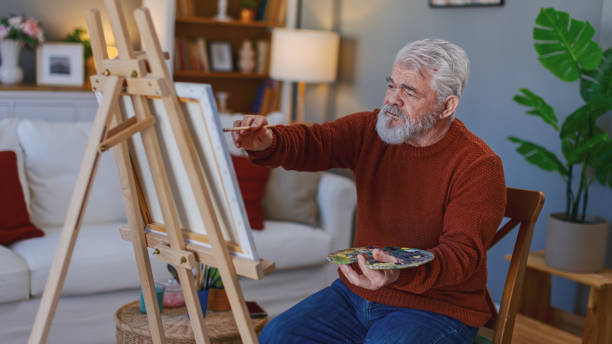 istock Senior man draws on canvas in his home 2205586274