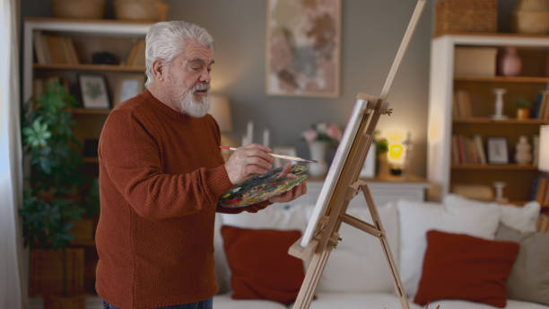 istock Senior man draws on canvas in his home 2205586285