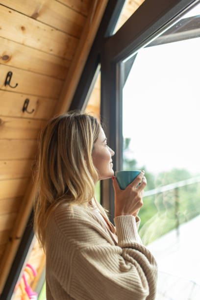 istock Woman drinking coffee and looking outside the window 2205586688