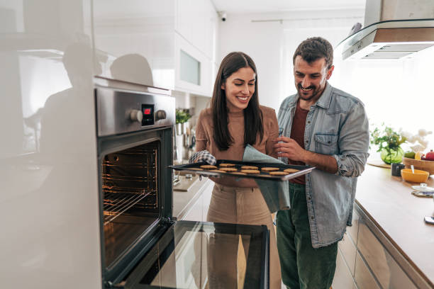 istock Happy couple baking cookies together in modern kitchen 2205587246