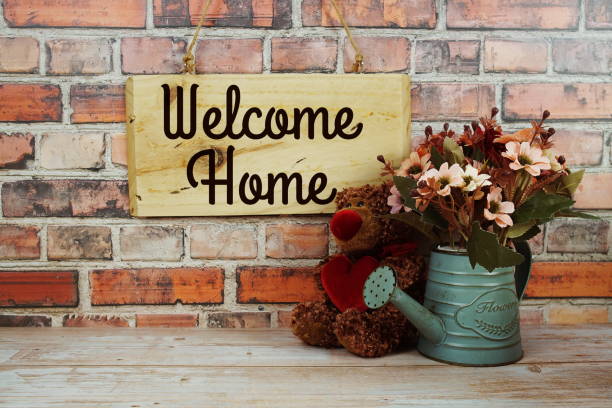 istock Welcome Home text on wooden sign hanging on old brick wall background 2205588097