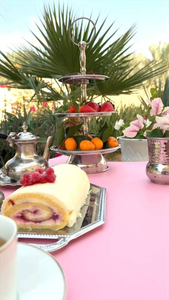 istock Cake roll displayed near cup on wooden surface, berry-topped cake swirls complement rustic tones, silver tray enhancing natural dessert appeal. Cup completes cozy cake setup. Wooden picnic concept. 2205590242