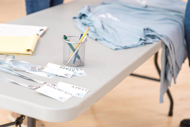 Staff and volunteer name tags, pens, and folded t-shirts on a table.