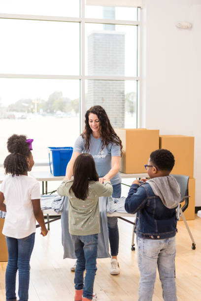 istock Volunteer Helping Children Sort Clothes at a Charity 2205590267